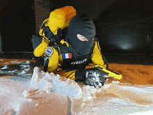 a man wearing a gign vest laying in the snow