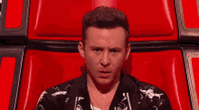 a man is sitting in a red chair and looking at the camera
