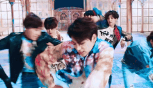 a group of young men are dancing in a room in front of a window .