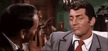 two men in suits and ties are kissing each other in a room .