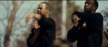 two men in black shirts are dancing together in a park