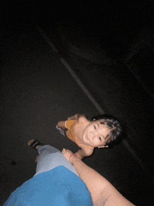a little girl is looking up at the camera while holding a woman 's hand
