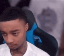a young man is sitting in a blue and black gaming chair looking at the camera .