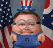 a man wearing a hat and glasses is holding a toy minion .