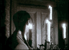 a man in a suit is standing in a dark room with candles in the background .