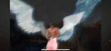 a man with angel wings is standing in the dark .