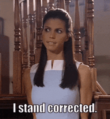 a woman in a blue dress stands in front of a wooden railing and says i stand corrected