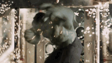 the hulk is being punched by a man in a room with sparks coming out of it .