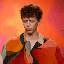 a man wearing a colorful shirt is making a funny face