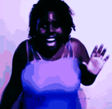 a woman in a purple tank top is waving