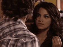 a woman in a plaid shirt looks at a man