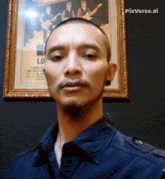 a man stands in front of a framed picture of a band called lo