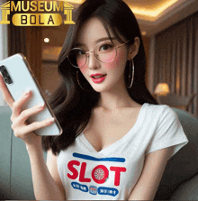 a woman wearing glasses and a slot t-shirt is holding a cell phone