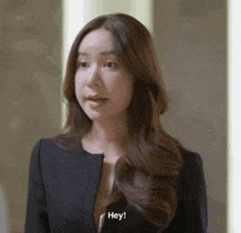 a woman in a black suit says hey in front of her face