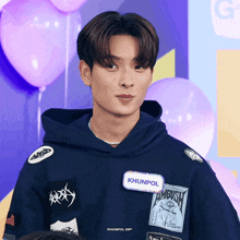 a man in a blue hoodie has a name tag that says khunpol