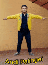 a man in a yellow jacket is standing with his arms outstretched and the name andi palingei on the bottom right