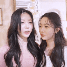 two women standing next to each other with one wearing a pink cardigan