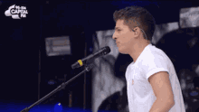 a man singing into a microphone with capital fm on the bottom right