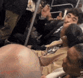 a man in a suit and tie is sitting next to a woman on a subway train .