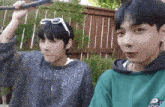 two young men are sitting next to each other and one of them is holding a rope .