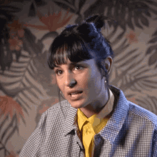 a woman wearing a plaid shirt and a yellow shirt is making a face