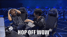 two men are sitting in chairs with their hands on their heads while a crowd watches .