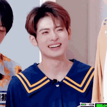 a young man wearing a blue shirt with yellow stripes on the collar is laughing .