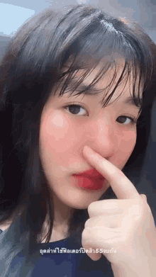 a close up of a girl holding her nose with a foreign language on the bottom