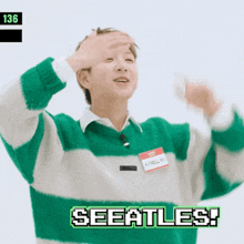 a man wearing a green and white striped sweater with the words seeattles on the bottom