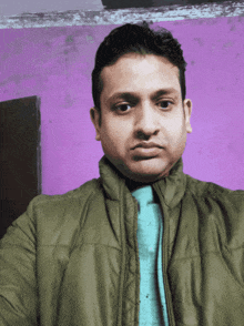 a man wearing a green jacket and a blue tie looks at the camera