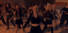 a group of women are dancing in a desert