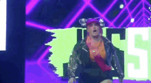 a man in a pink hat is dancing on a stage in front of a neon sign that says ' ts ' .