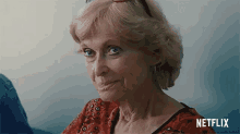 a woman in a red shirt with a netflix logo behind her