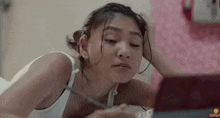 a young woman is laying on a bed and looking at herself in the mirror .