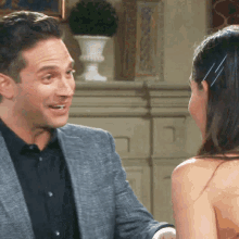 a man in a suit is talking to a woman in a black dress