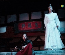 a man in a white robe is standing next to another man in a red robe