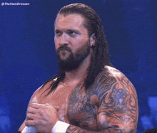 a man with long hair and a beard is standing in front of a blue background that says thekamdreesen