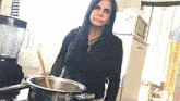 a woman is stirring a pot of soup with a wooden spoon in a kitchen .