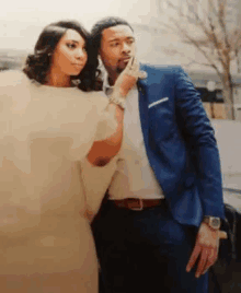 a man in a blue suit and a woman in a white dress standing next to each other