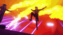 a man is standing on one leg in front of a fire while another man stands behind him .