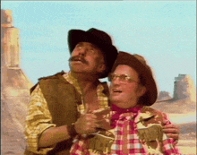 two men in cowboy hats and plaid shirts are hugging each other