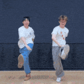 two men are dancing in front of a wall with the letter u on it