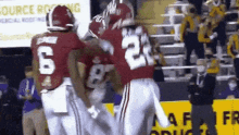 a group of football players are celebrating a touchdown in front of a sign that says " source racing "