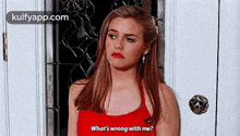 a woman in a red tank top is standing in front of a door and asking what 's wrong with me ?