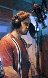 a man wearing headphones is singing into a microphone in a studio .