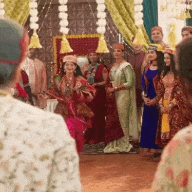 a group of people are standing around a woman in a costume dancing in a room .