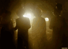 a group of people are standing in a dark room and the words diskomo are on the bottom right