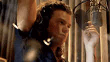 a man is singing into a microphone in a recording studio while wearing headphones .