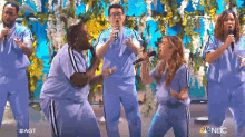 a group of people in scrubs are singing into microphones on stage