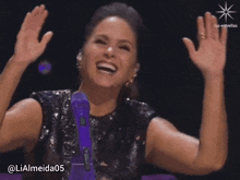a woman in a black sequined dress is smiling and raising her hands in the air
